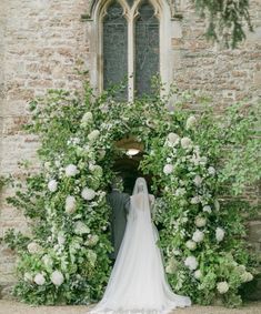 a bride and groom are standing in front of an archway with white flowers on it