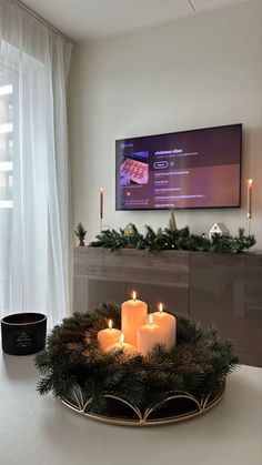 candles are arranged on a tray in front of a flat screen tv with christmas decorations