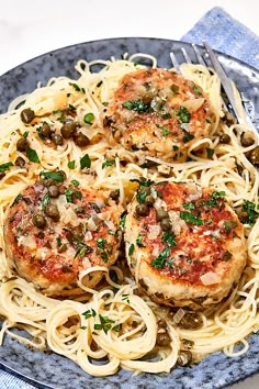 three meat patties with pasta and olives on a plate next to a fork