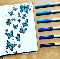 an open notebook with blue butterflies and the words may written in black ink on it