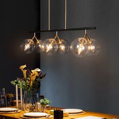 a dining room table with plates and flowers in vases hanging from the light fixture