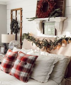 a bed topped with pillows covered in blankets and christmas wreaths on top of it