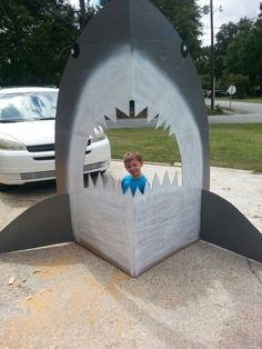 a little boy sitting in a shark shaped cardboard box