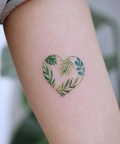 a heart shaped tattoo with green leaves on the back of her left arm and shoulder