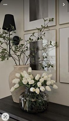 a vase filled with white flowers sitting on top of a wooden table next to pictures