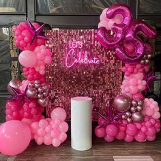 balloons and streamers are set up in front of a pink 30th birthday party backdrop