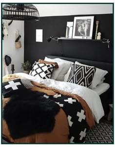 a bedroom with black and white bedding, pillows and pictures on the wall above it