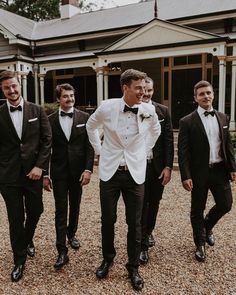 a group of men in tuxedos standing next to each other near a house