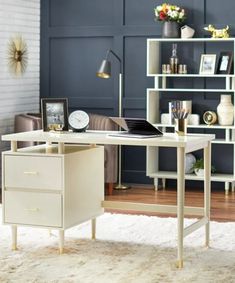 a white desk sitting on top of a rug in front of a book shelf filled with books