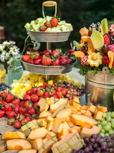 an assortment of fruits and vegetables are arranged in buckets on a table with flowers