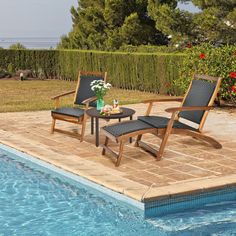 two lawn chairs sitting next to a swimming pool with flowers on the table in front of it