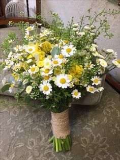 a bouquet of daisies and other flowers on a table in front of a couch