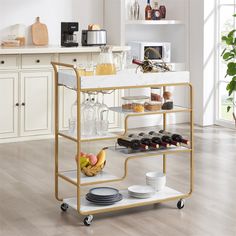 a kitchen cart with wine glasses, plates and cups on it in front of a counter