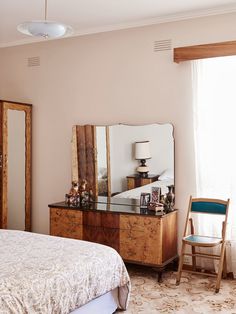 a bedroom with a bed, dresser and mirror