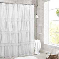 a white shower curtain in a bathroom next to a window and rug on the floor