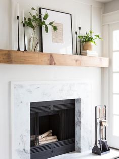 a white fireplace with some plants on the mantel above it and other decor items