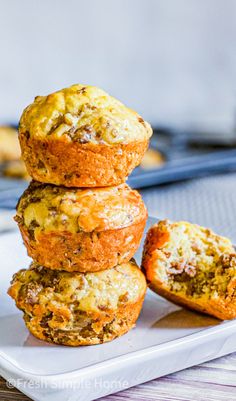 three muffins stacked on top of each other on a white plate with bananas in the background