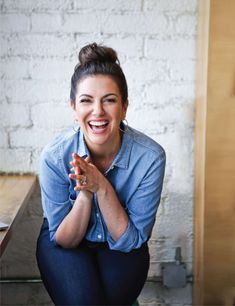 a woman sitting on the ground smiling and holding her hands together