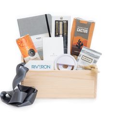 a wooden box filled with various items on top of a white surface and black ribbon