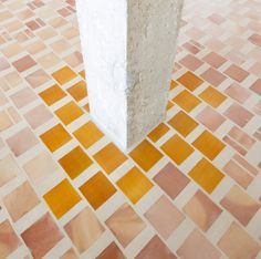 a tall white pillar sitting in the middle of a tiled floor covered in yellow squares