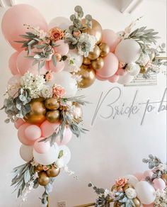 a bunch of balloons and flowers hanging from the ceiling in front of a white wall