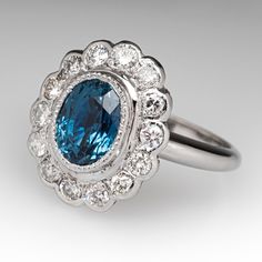 an oval blue and white diamond ring with diamonds around the band, set in 18k white gold