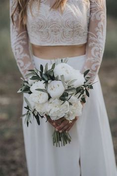 a woman holding a bouquet of white flowers