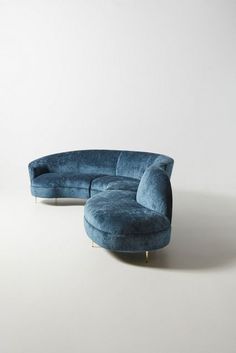 a large blue couch sitting on top of a white floor next to a chair and ottoman