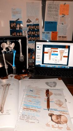 a laptop computer sitting on top of a desk next to an open book and medical diagrams