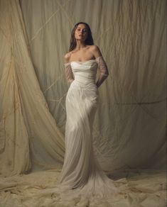 a woman in a white dress is posing for a photo with her hands on her hips