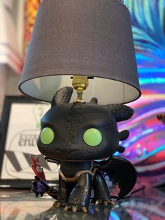 a lamp that is on top of a table with a dragon figurine underneath it