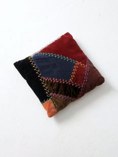 a multicolored patchwork pillow sitting on top of a white table