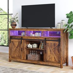 an entertainment center with purple lighting in the corner and a television on it's stand