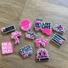 several pink and black stickers sitting on top of a wooden table next to each other