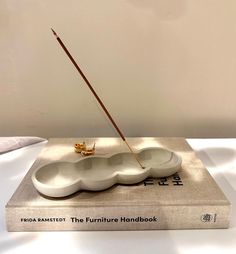 a book with a white sculpture on top and a wooden stick sticking out of it