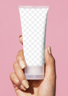 a hand holding a tube of cream on a pink background