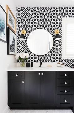 a black and white bathroom with an oval mirror on the wall above the vanity, along with two framed pictures