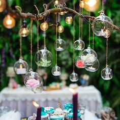 a table topped with lots of cupcakes covered in frosting and hanging from branches