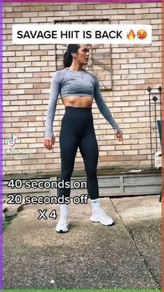 a woman standing in front of a brick wall wearing leggings and sports bra