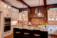 a large kitchen with an island and brick wall in the center, surrounded by stools