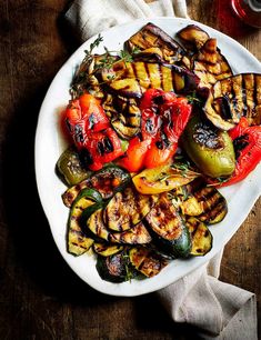 a white plate topped with grilled vegetables on top of a wooden table