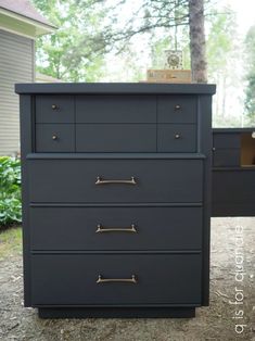 a black dresser with gold handles in front of a house