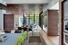 an open kitchen and dining area with wood paneling on the walls, stainless steel appliances in the foreground