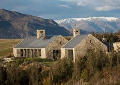 an old stone house with mountains in the background