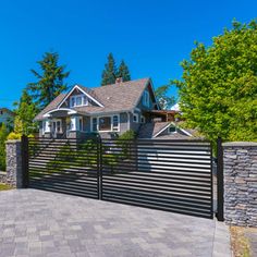 a house with a black fence in front of it and some trees on the other side