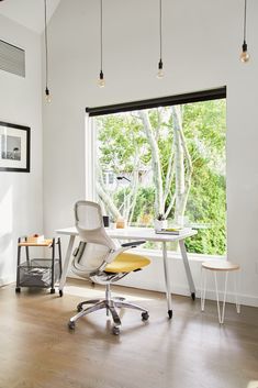 an office with a desk and chair in front of a large window that looks out onto the trees outside