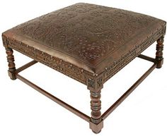 a brown leather ottoman sitting on top of a wooden table