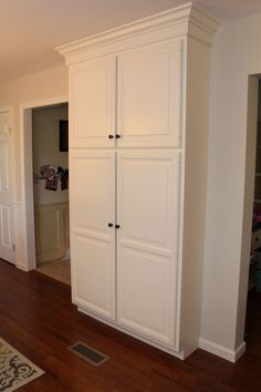 a large white cabinet in the corner of a room with hardwood floors and hard wood flooring