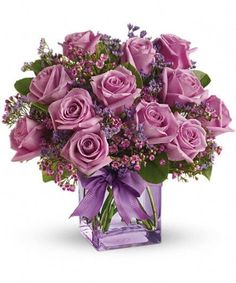 a purple vase filled with lots of pink roses