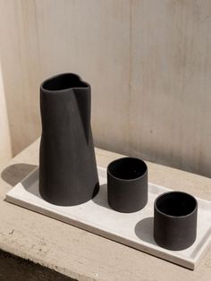 three black vases sitting on top of a white tray